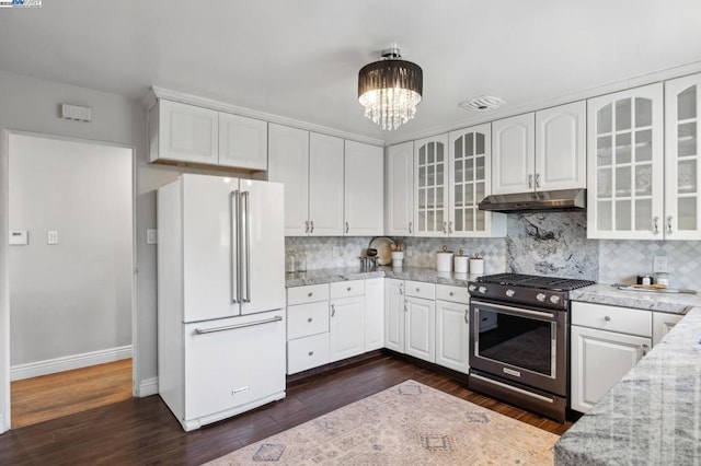 kitchen featuring dark hardwood / wood-style floors, white cabinetry, high end white refrigerator, stainless steel gas range oven, and light stone countertops