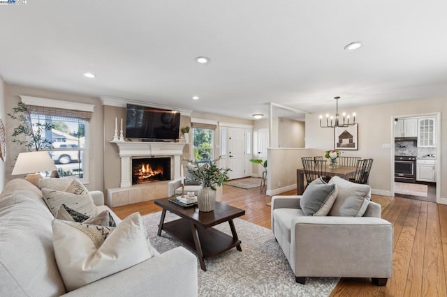 living room featuring light hardwood / wood-style flooring, a fireplace, and an inviting chandelier