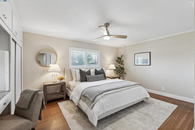 bedroom featuring ornamental molding, dark wood-type flooring, ceiling fan, and a closet