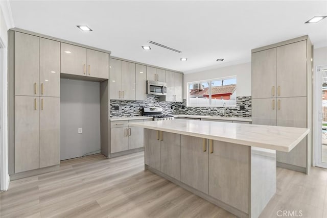 kitchen with sink, light hardwood / wood-style floors, a center island, and appliances with stainless steel finishes