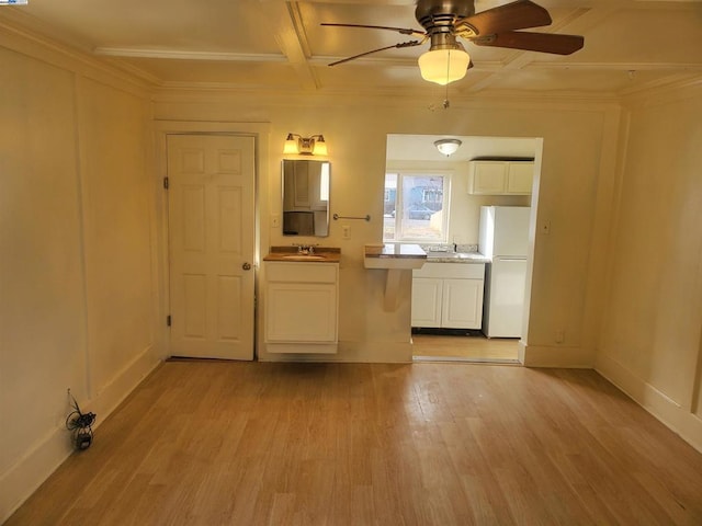 empty room with coffered ceiling, sink, ceiling fan, and light hardwood / wood-style flooring