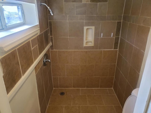 bathroom featuring tiled shower and toilet