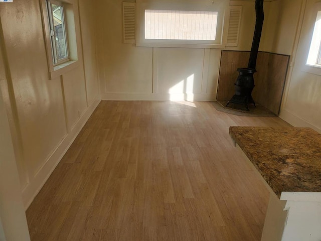 empty room with light wood-type flooring and a wood stove