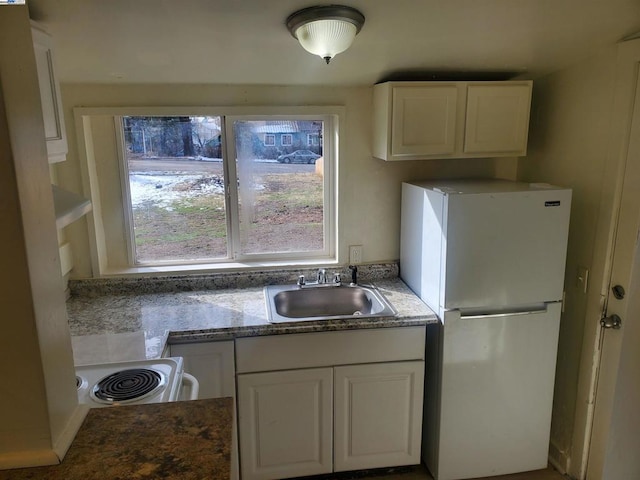 kitchen featuring white refrigerator, white cabinetry, range, and sink