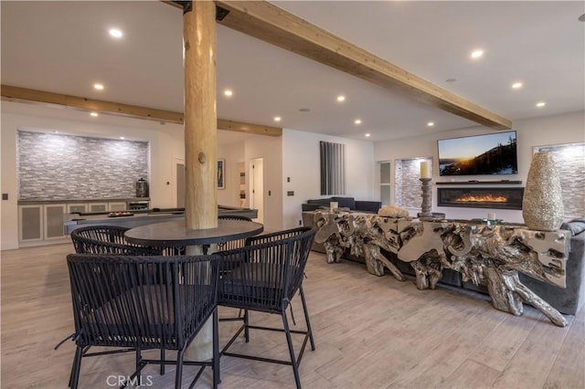 dining room featuring light hardwood / wood-style flooring and beamed ceiling