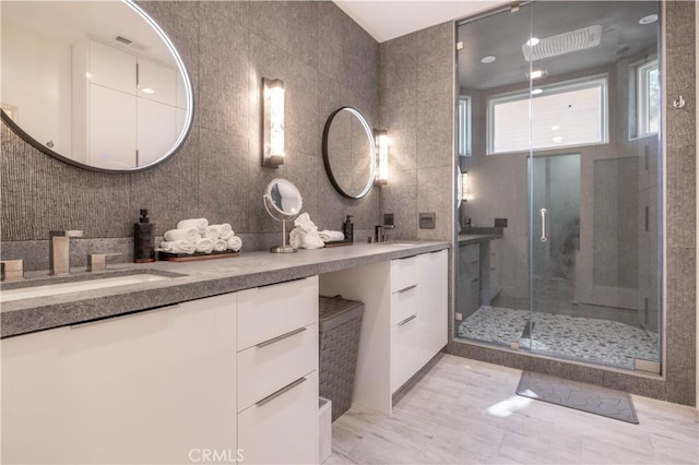 bathroom featuring vanity, a shower with shower door, and tile walls