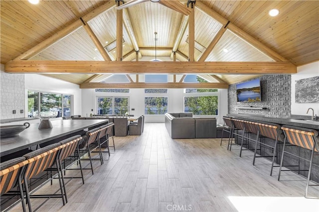 dining room with beamed ceiling, sink, wooden ceiling, and high vaulted ceiling