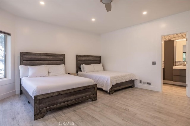 bedroom featuring connected bathroom, light hardwood / wood-style floors, and ceiling fan