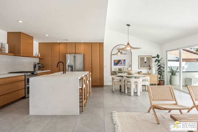 kitchen featuring sink, vaulted ceiling, hanging light fixtures, an island with sink, and stainless steel appliances