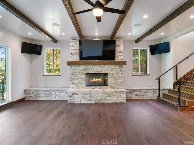 unfurnished living room with hardwood / wood-style flooring, a fireplace, beam ceiling, and a wealth of natural light