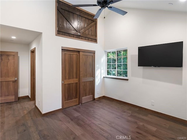 unfurnished bedroom with dark hardwood / wood-style flooring, high vaulted ceiling, and ceiling fan