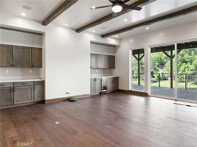 unfurnished living room with ceiling fan, dark hardwood / wood-style floors, and beam ceiling