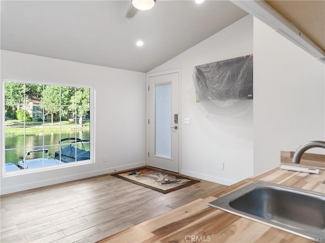 interior space featuring lofted ceiling, sink, and light hardwood / wood-style floors