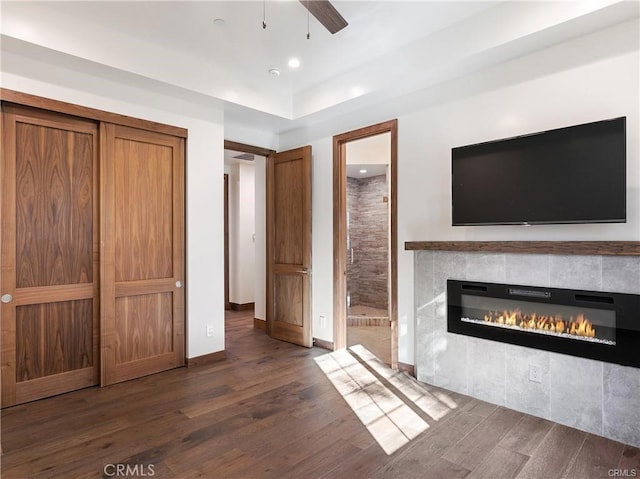 unfurnished living room featuring a fireplace, dark hardwood / wood-style floors, and ceiling fan