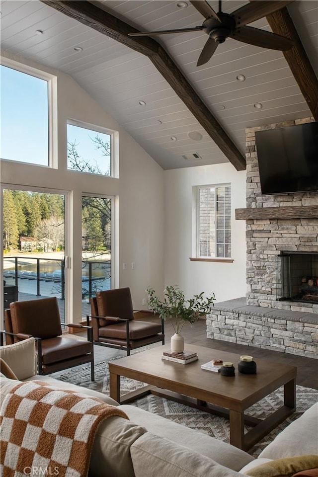 living room with a stone fireplace, high vaulted ceiling, wood-type flooring, ceiling fan, and beam ceiling