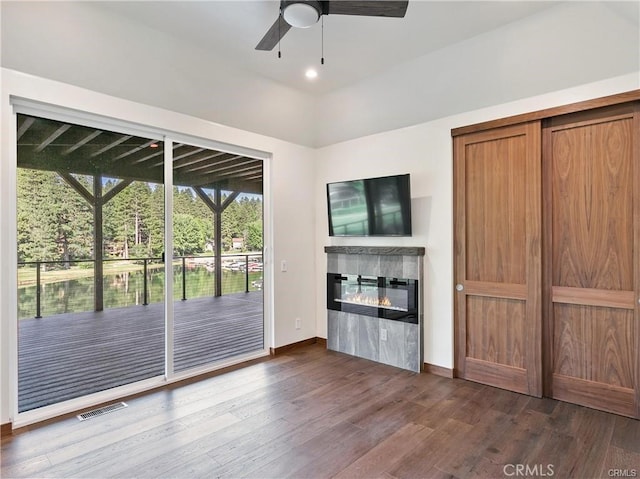 unfurnished living room featuring dark wood-type flooring and ceiling fan