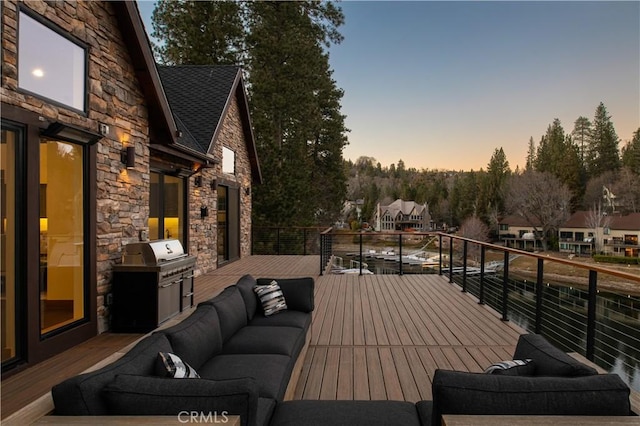 deck at dusk with grilling area and an outdoor hangout area