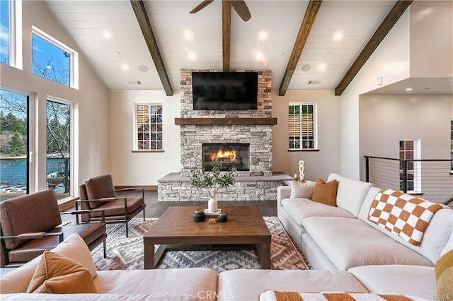 living room featuring ceiling fan, a fireplace, and vaulted ceiling with beams