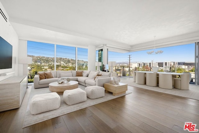 living room featuring a wall of windows, a chandelier, and light wood-type flooring