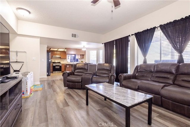 living room featuring ceiling fan, a healthy amount of sunlight, and light wood-type flooring