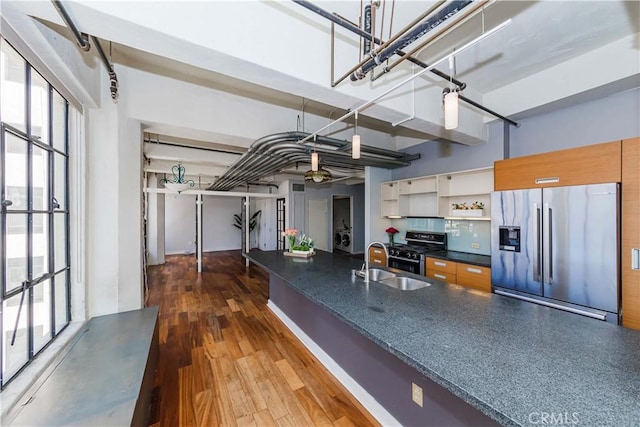 kitchen with sink, tasteful backsplash, wood-type flooring, stainless steel fridge with ice dispenser, and range with gas stovetop