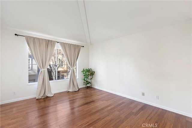 unfurnished room with lofted ceiling with beams, baseboards, and wood finished floors