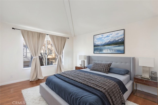 bedroom featuring hardwood / wood-style floors and lofted ceiling with beams