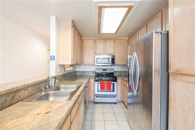 kitchen with a sink, appliances with stainless steel finishes, light brown cabinetry, and light tile patterned floors