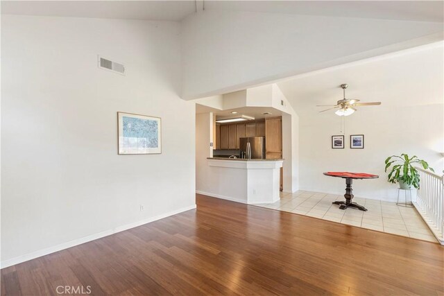 unfurnished living room featuring ceiling fan, high vaulted ceiling, and light hardwood / wood-style floors