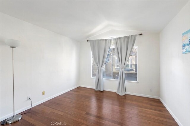 empty room with vaulted ceiling and dark hardwood / wood-style floors