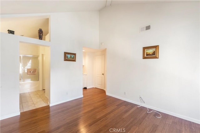 unfurnished room featuring hardwood / wood-style floors and high vaulted ceiling