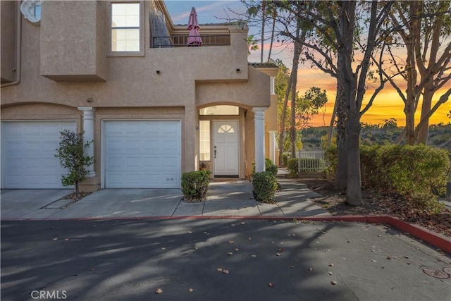 view of front facade with concrete driveway, a balcony, and stucco siding