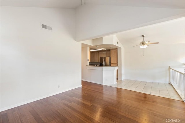 unfurnished living room featuring visible vents, light wood-style flooring, baseboards, and ceiling fan