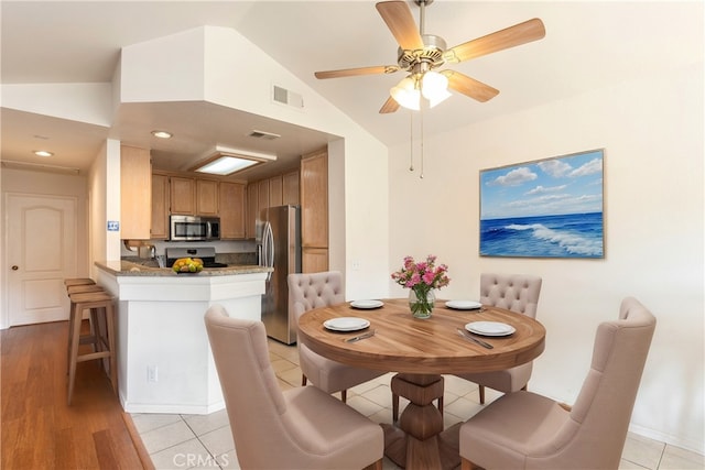 dining space featuring light tile patterned floors, visible vents, and lofted ceiling