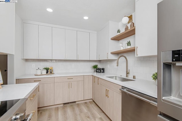 kitchen with sink, stainless steel dishwasher, backsplash, and light hardwood / wood-style floors