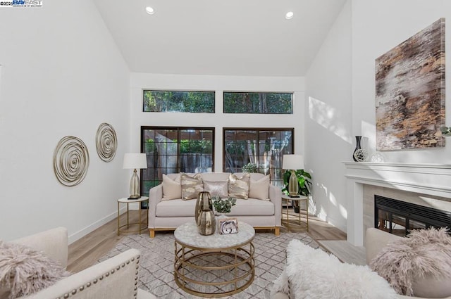 living room featuring a fireplace, high vaulted ceiling, and light hardwood / wood-style flooring