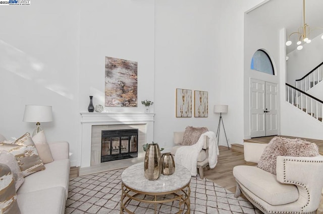 living room featuring a towering ceiling, a chandelier, and light wood-type flooring