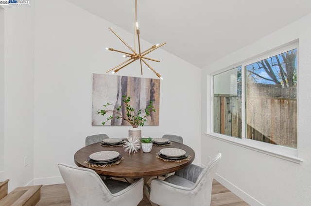 dining room with lofted ceiling, an inviting chandelier, and light hardwood / wood-style floors