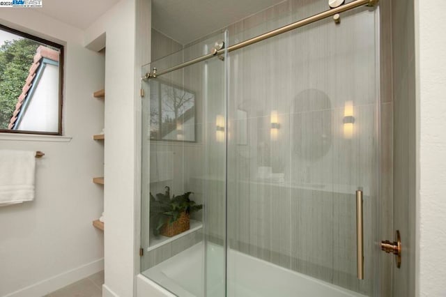 bathroom with tile patterned floors and shower / bath combination with glass door