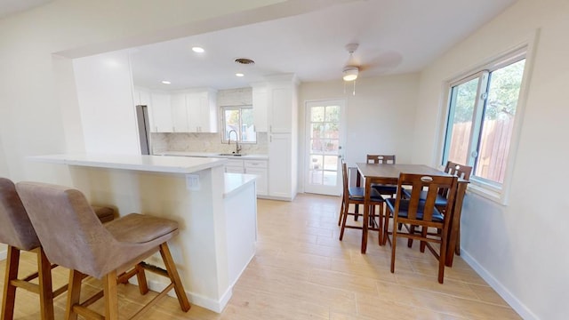 kitchen featuring a breakfast bar, sink, tasteful backsplash, kitchen peninsula, and white cabinets