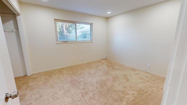 unfurnished bedroom featuring light carpet and a closet