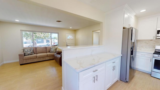 kitchen with stainless steel appliances, light stone counters, white cabinets, decorative backsplash, and kitchen peninsula