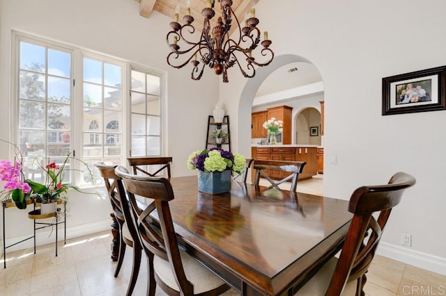 tiled dining space with an inviting chandelier and beamed ceiling