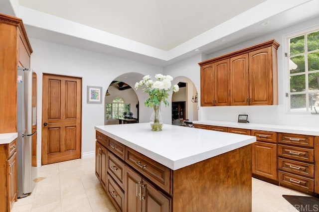 kitchen with tasteful backsplash, a center island, light tile patterned floors, and stainless steel refrigerator