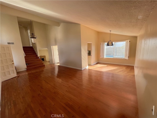 unfurnished room featuring hardwood / wood-style flooring, lofted ceiling, and a textured ceiling