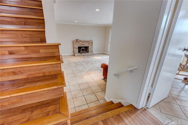 staircase featuring crown molding, a fireplace, and tile patterned floors