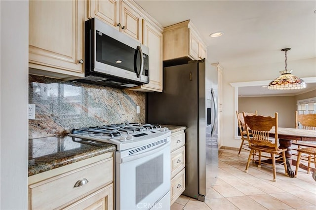 kitchen featuring tasteful backsplash, dark stone counters, pendant lighting, stainless steel appliances, and cream cabinets