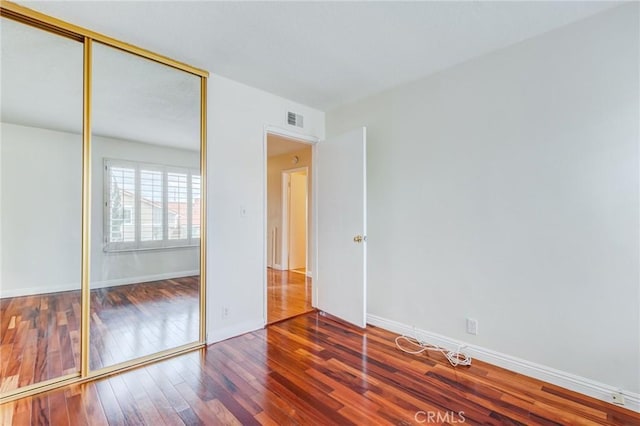 unfurnished bedroom featuring wood-type flooring and a closet