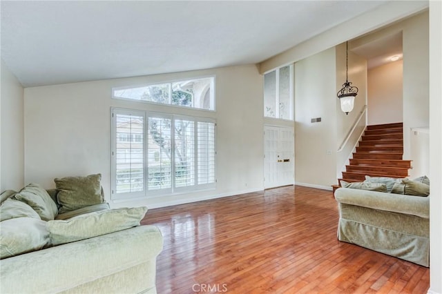 living room with high vaulted ceiling, a healthy amount of sunlight, and hardwood / wood-style floors