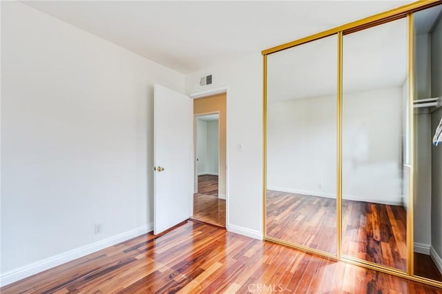 unfurnished bedroom featuring hardwood / wood-style floors and a closet